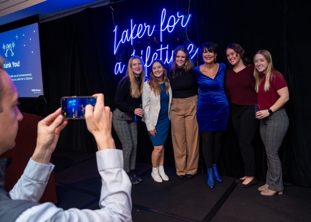 Kyle from the Alumni House takes picture of group of girls with President Mantella